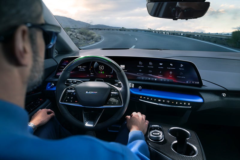 Front View of the 2026 OPTIQ-V Driving Through the Dusk Utilizing its Headlights | Coughlin Cadillac Marysville in Marysville OH
